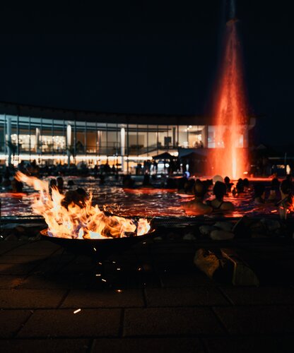 Feuershow im Spa Resort Geinberg mit Flammen, Wasserfontäne und Badegästen bei Nacht