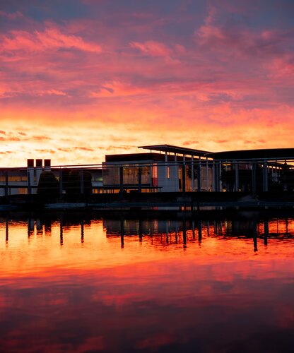 Gebäude am Wasser unter einem rot-orangefarbenen Himmel bei Sonnenuntergang