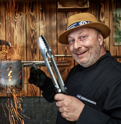 Grillweltmeister Adi Bittermann mit Grillwerkzeug und Feuer | © Adi Bittermann