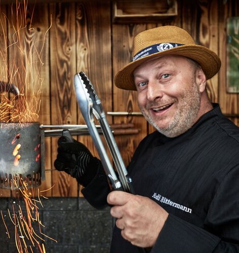 Grillweltmeister Adi Bittermann mit Grillwerkzeug und Feuer | © Adi Bittermann