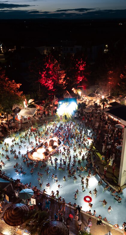 Beleuchtete Poolparty mit vielen Menschen bei Nacht | © Spa Resort Geinberg / Tobi Gast