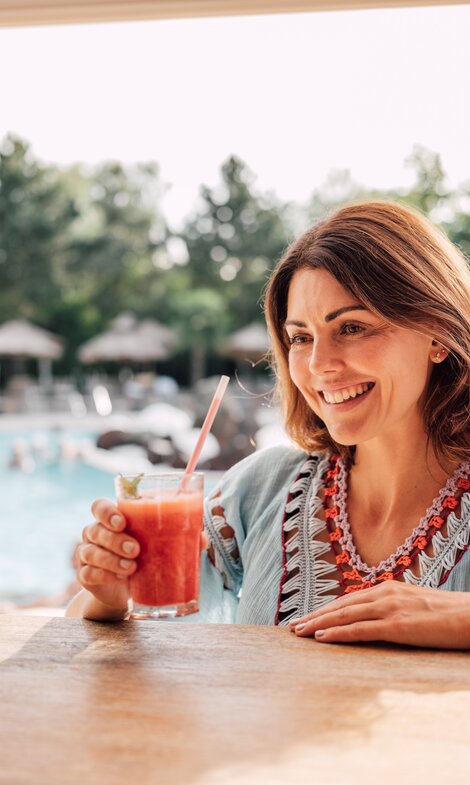 Brünette Frau genießt einen exotischen Cocktail an der Karibik-Bar im Spa Resort Geinberg  | © Spa Resort Geinberg / Chris Perkles