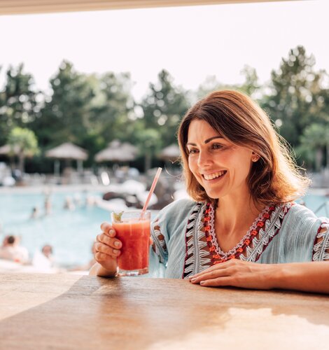Brünette Frau genießt einen exotischen Cocktail an der Karibik-Bar im Spa Resort Geinberg  | © Spa Resort Geinberg / Chris Perkles