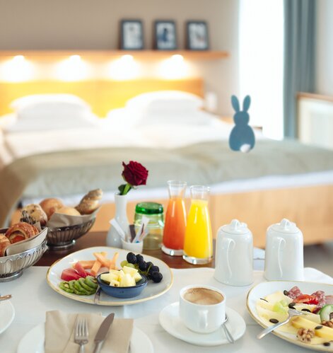 Reichhaltiges Frühstück auf Tisch vor Hotelbett