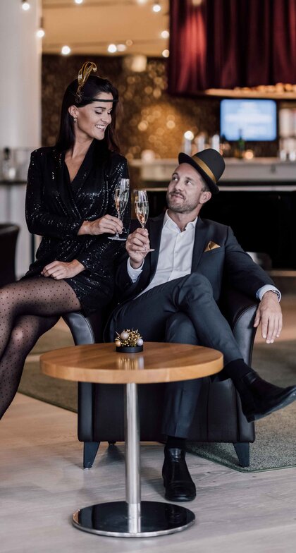 Passend zu den golden 20ies gekleidetes Paar stoßt in der Hotelbar auf das neue Jahr an | © Spa Resort Geinberg / Chris Perkles 