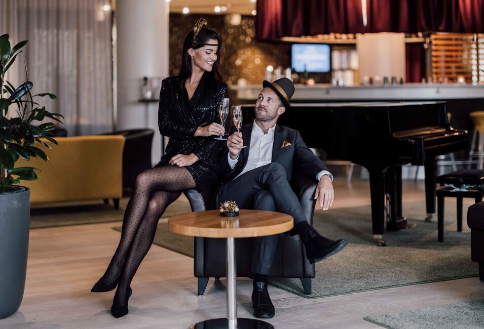 Passend zu den golden 20ies gekleidetes Paar stoßt in der Hotelbar auf das neue Jahr an | © Spa Resort Geinberg / Chris Perkles 