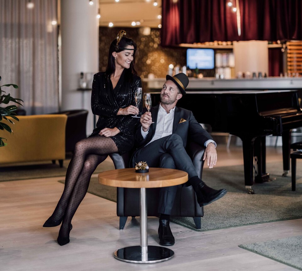 Passend zu den golden 20ies gekleidetes Paar stoßt in der Hotelbar auf das neue Jahr an | © Spa Resort Geinberg / Chris Perkles 