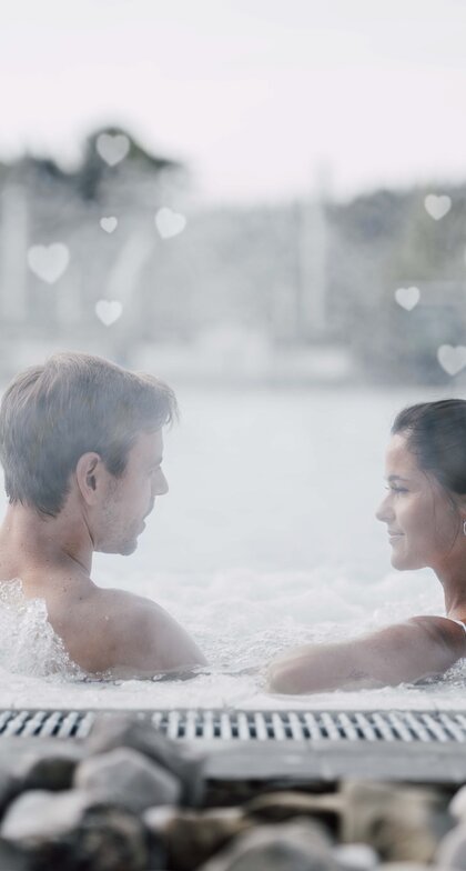 Paar im sprudelnden Whirlpool mit Dampfherzen