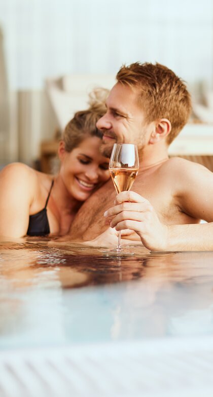 Verliebtes Paar entspannt mit einem Glas Champagner im Whirlpool der Geinberg5 Private Spa Villas | © Spa Resort Geinberg / Julia Traxler