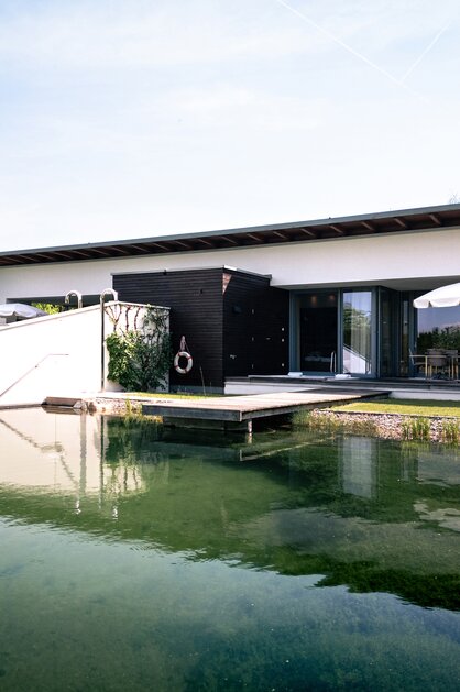 Moderne Villa am Wasser mit Terrasse und Sonnenschirm im Frühling | © Spa Resort Geinberg / Tobi Gast