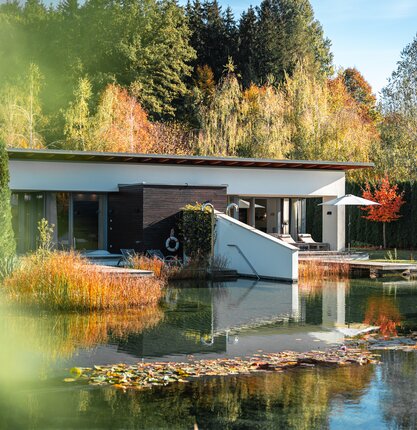 Moderne Villa am See im Herbstwald mit Spiegelung im Wasser | © Spa Resort Geinberg / Tobi Gast