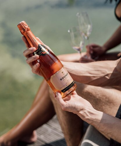 Personen mit Crémant-Flasche am Badesteg