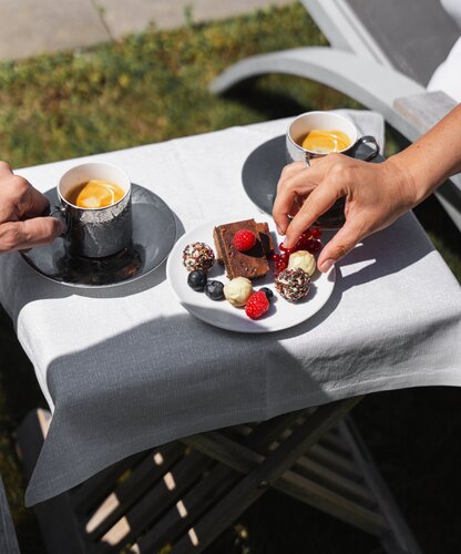 Dessertteller mit Pralinen, Brownie und Beeren neben zwei Tassen auf einem Tablett
