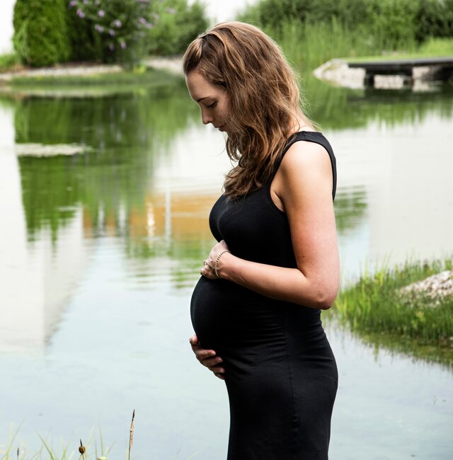 Schwangere Frau im schwarzen Kleid am Teich | © Spa Resort Geinberg / Juliane Mayr