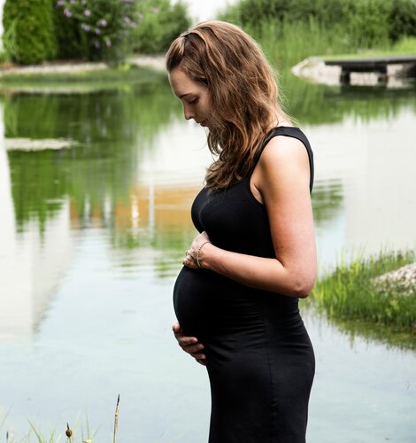 Schwangere Frau im schwarzen Kleid am Teich | © Spa Resort Geinberg / Juliane Mayr