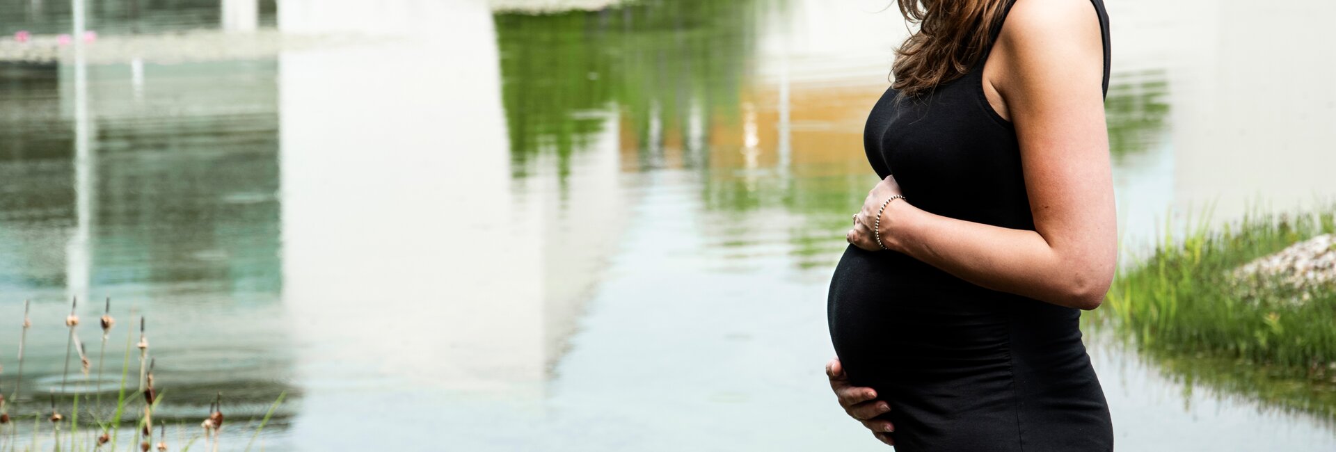 Schwangere Frau im schwarzen Kleid am Teich | © Spa Resort Geinberg / Juliane Mayr