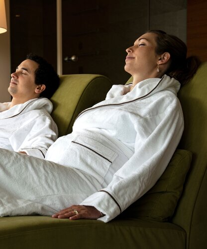 Entspanntes schwangeres Paar in Bademänteln auf Liegen | © Spa Resort Geinberg / Juliane Mayr
