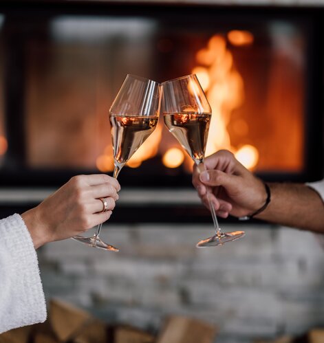 Zwei Champagner-Gläser stoßen vor dem Kamin in der Private Spa Suite an | © Spa Resort Geinberg / Chris Perkles