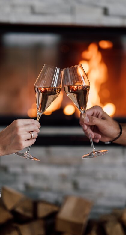 Zwei Champagner-Gläser stoßen vor dem Kamin in der Private Spa Suite an | © Spa Resort Geinberg / Chris Perkles