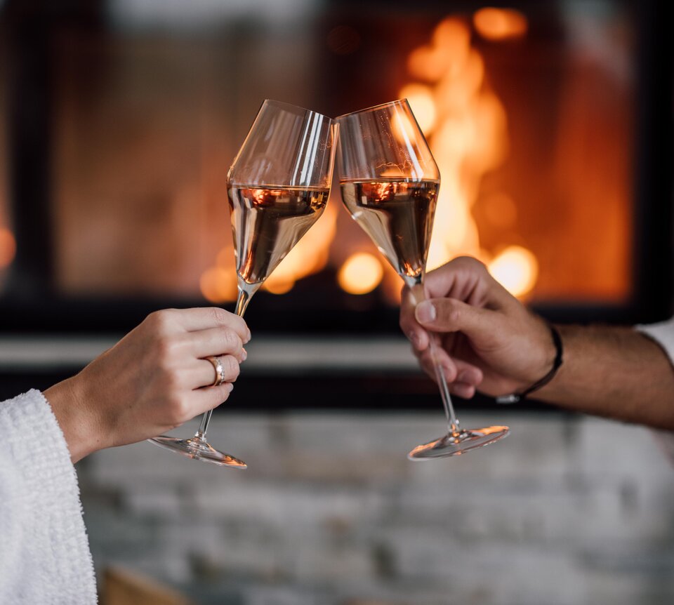 Zwei Champagner-Gläser stoßen vor dem Kamin in der Private Spa Suite an | © Spa Resort Geinberg / Chris Perkles