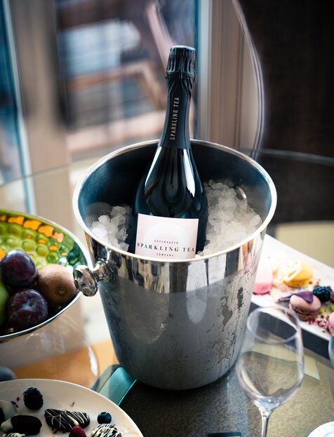 Champagnerflasche in Eiswürfeln im silbernen Kübel neben Obstschale | © Spa Resort Geinberg / Tobi Gast
