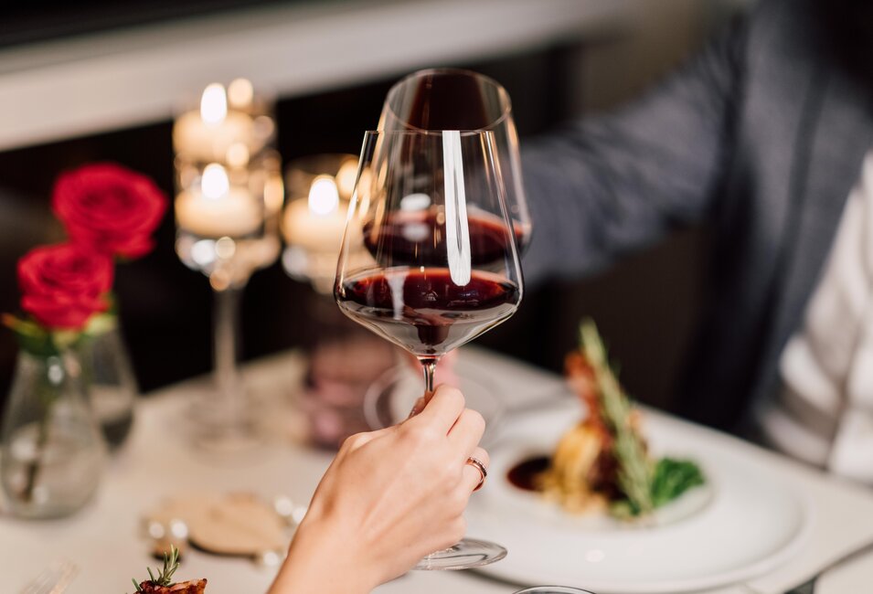 Zwei Gläser mit Rotwein stoßen beim Candlelight-Dinner im Geinberg5 Restaurant miteinander an | © Spa Resort Geinberg / Chris Perkles