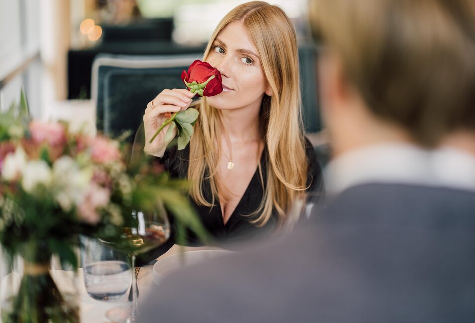 Frau riecht an einer roten Rose beim romantischen Dinner im Geinberg5 Restaurant in Oberösterreich | © Spa Resort Geinberg / Chris Perkles