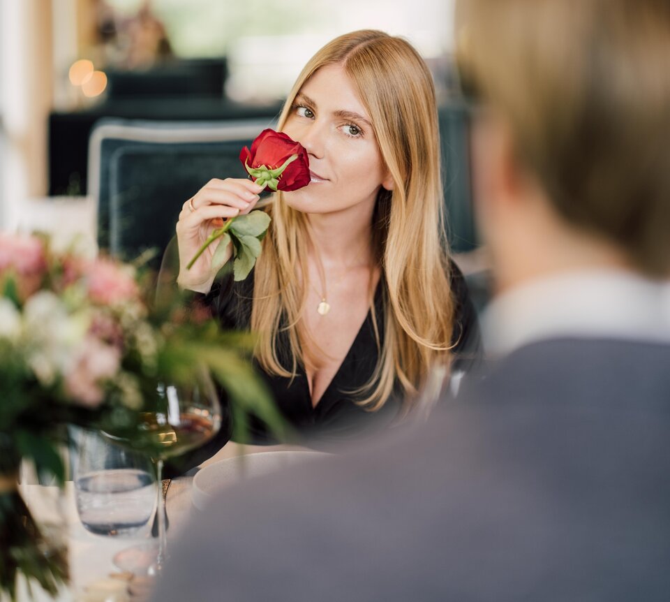 Frau riecht an einer roten Rose beim romantischen Dinner im Geinberg5 Restaurant in Oberösterreich | © Spa Resort Geinberg / Chris Perkles