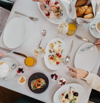 Frühstückstisch mit Wurst, Käse, Gebäck, Lachsbrötchen, Joghurt, Orangensaft und Kaffee von oben | © Spa Resort Geinberg / Chris Perkles