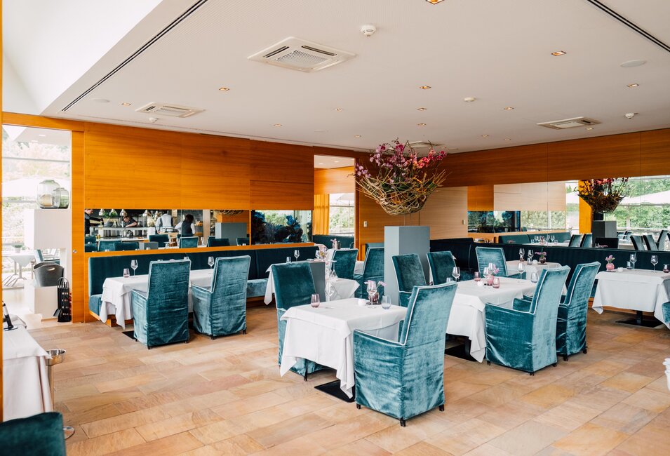 Räumlichkeiten des Geinberg5 Restaurants mit gedeckten Tischen und blauen, gepolsterten Stühlen | © Spa Resort Geinberg