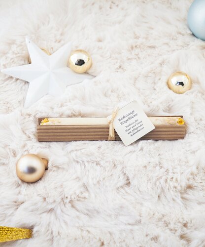 Badestange in Geschenkverpackung auf flauschigem Untergrund mit Weihnachtskugeln und Stern