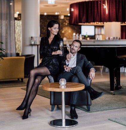 Stilvoller Abend an der Hotelbar | © Spa Resort Geinberg / Chris Perkles Elegant gekleidetes Paar verbringt den Abend an der Hotelbar mit zwei Gläsern Sekt | © Spa Resort Geinberg / Chris Perkles