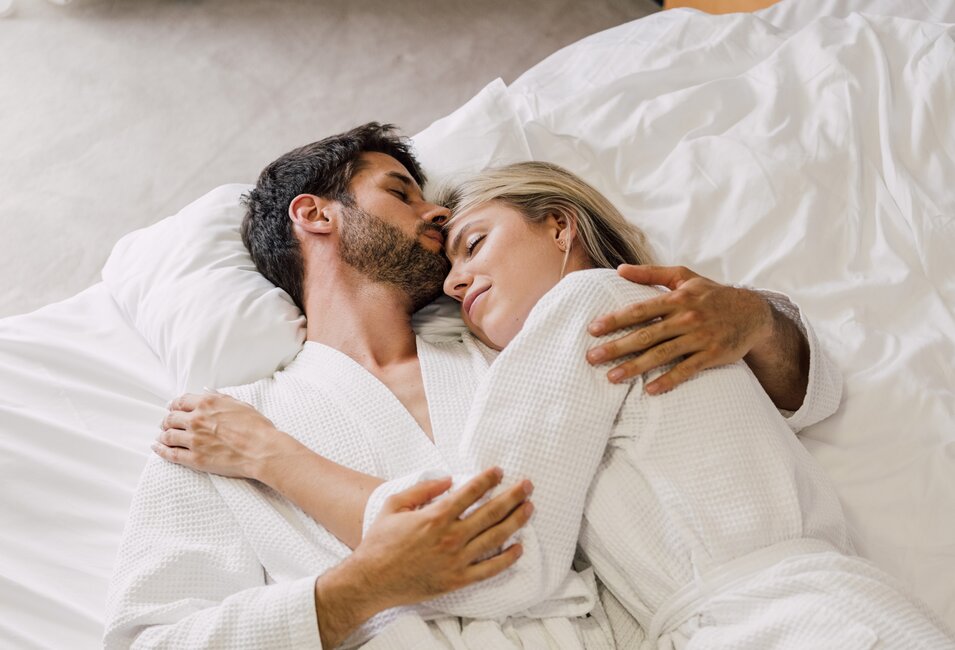 Paar im Bademantel entspannt in seinem Hotelbett im Spa Resort Geinberg | © Spa Resort Geinberg / Chris Perkles