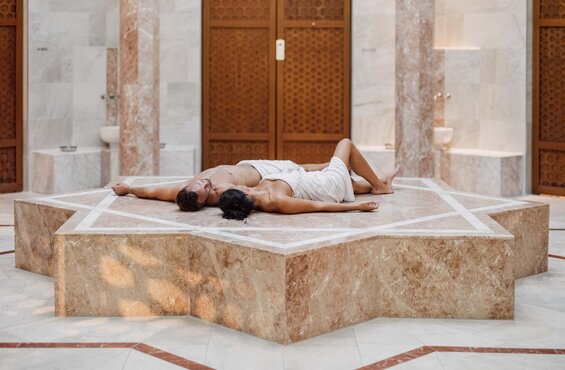 Paar entspannt beim Hamam-Ritual am beheizten Nabelstein in der Oriental World des Spa Resort Geinberg | © Spa Resort Geinberg / Chris Perkles