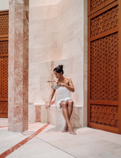 Frau gießt Wasser über ihre Arme beim Hamam-Ritual in der Oriental World des Spa Resort Geinberg | © Spa Resort Geinberg / Chris Perkles