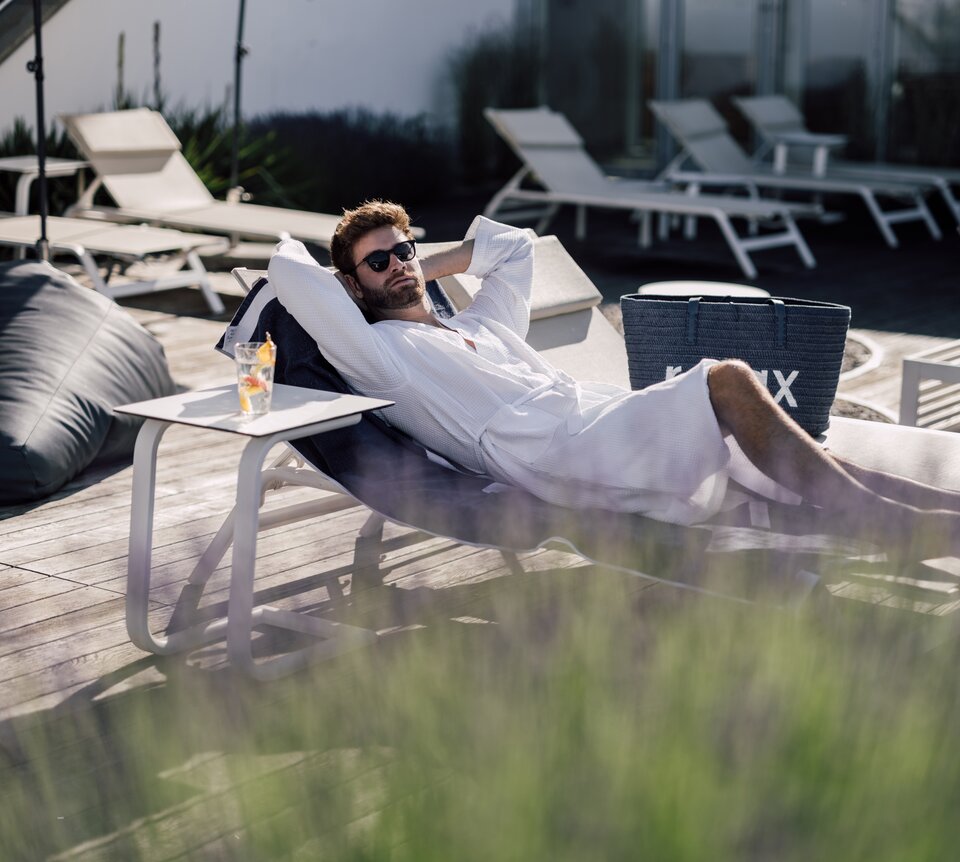 Mann mit Sonnenbrille entspannt auf einer Liege im Relax! Garten des Spa Resort Geinberg | © Spa Resort Geinberg / Chris Perkles