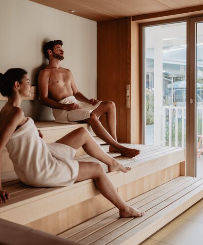 Paar mit Badetuch schwitzt in der Karibischen Saunawelt im Spa Resort Geinberg | © Spa Resort Geinberg / Chris Perkles