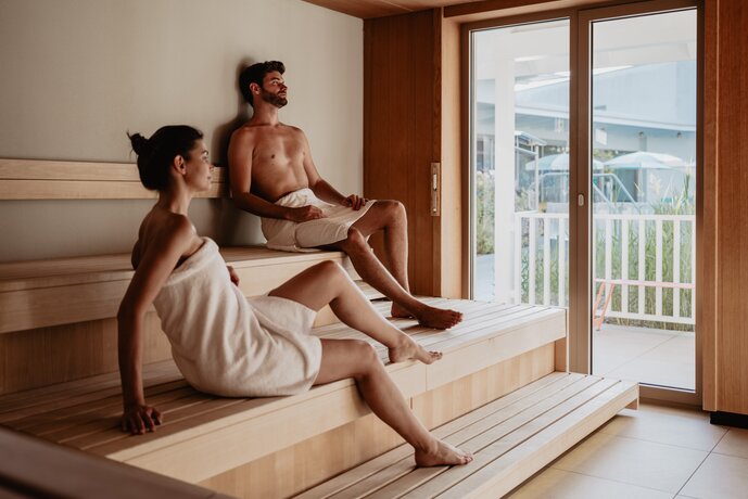 Paar mit Badetuch schwitzt in der Karibischen Saunawelt im Spa Resort Geinberg | © Spa Resort Geinberg / Chris Perkles