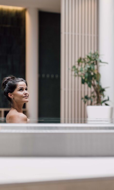 Dunkelhaarige Frau entspannt im Whirlpool in der Karibischen Saunawelt im Spa Resort Geinberg | © Spa Resort Geinberg / Chris Perkles