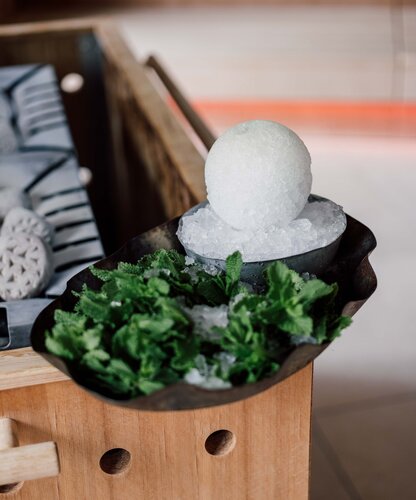 Eiskugel auf Eis, umgeben von Minze in einer Schale | © Spa Resort Geinberg / Chris Perkles