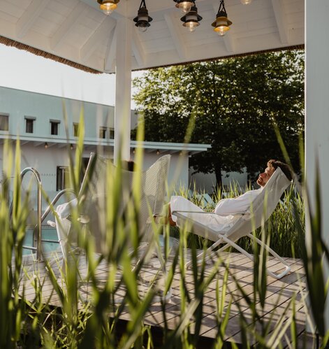 Paar genießt die Sonnenstrahlen im idyllischen Ambiente unter dem Pavillon der Karibischen Saunawelt | © Spa Resort Geinberg / Chris Perkles