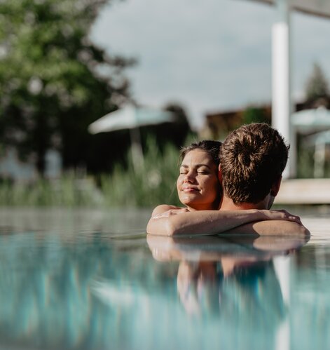 Paar genießt die Sonnenstrahlen im Pool der Karibischen Saunawelt im Spa Resort Geinberg | © Spa Resort Geinberg / Chris Perkles