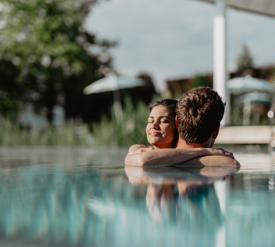 Paar genießt die Sonnenstrahlen im Pool der Karibischen Saunawelt im Spa Resort Geinberg | © Spa Resort Geinberg / Chris Perkles