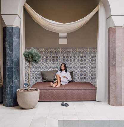 Entspannte Frau auf luxuriösem Daybed im SPAplus Arkadenhof | © Spa Resort Geinberg / Chris Perkles