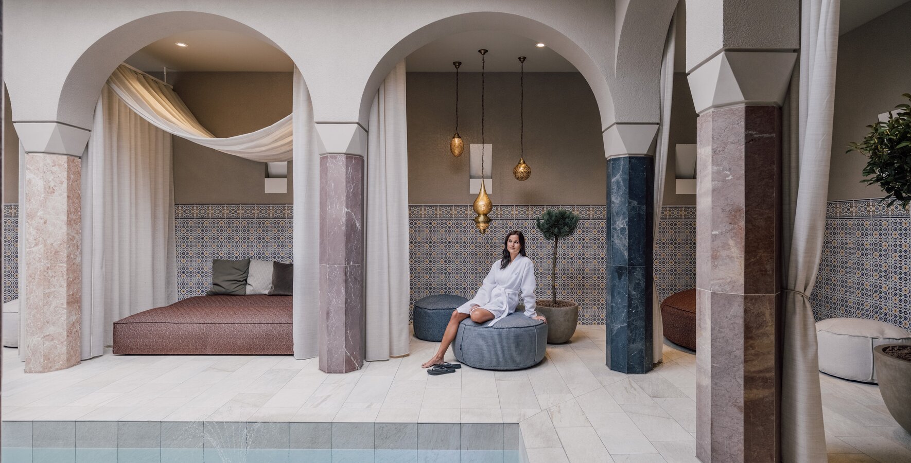Luxuriöser Wellnessbereich im SPAplus Arkadenhof mit Frau im Bademantel | © Spa Resort Geinberg / Chris Perkles