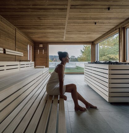 Frau entspannt in moderner Holzsauna mit Ausblick | © Spa Resort Geinberg / Chris Perkles