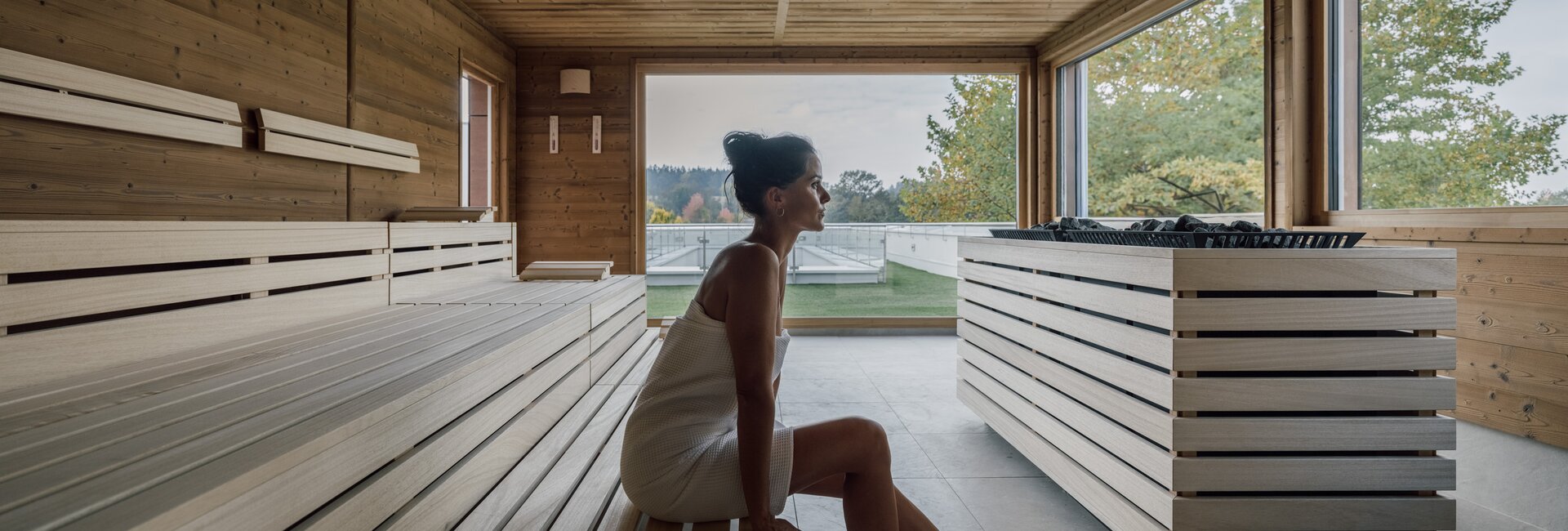 Frau entspannt in moderner Holzsauna mit Ausblick | © Spa Resort Geinberg / Chris Perkles