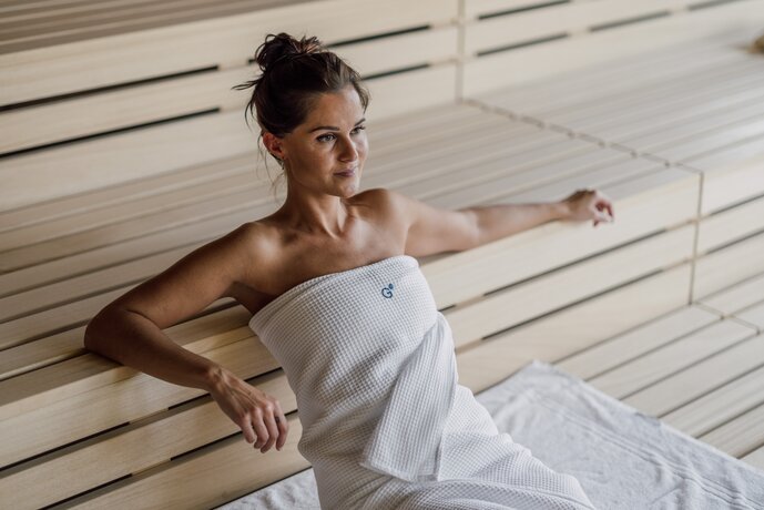 Frau im weißen Handtuch in Holzsauna | © Spa Resort Geinberg / Chris Perkles