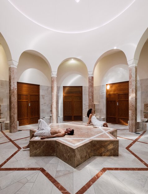 Paar genießt die Wärme des beheizten Nabelsteins in der Oriental World | © Spa Resort Geinberg / Chris Perkles