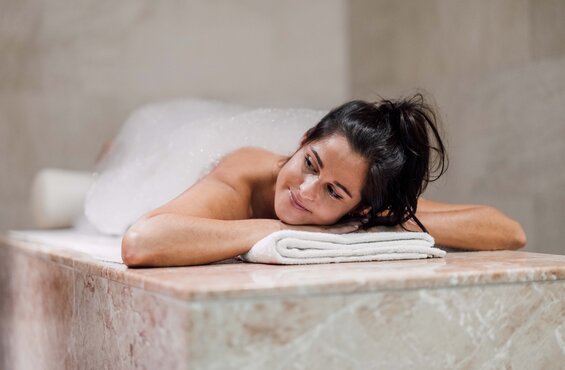 Frau liegt entspannt auf einer Liege für eine Seifenschaum-Massage im Spa Resort Geinberg | © Spa Resort Geinberg / Chris Perkles
